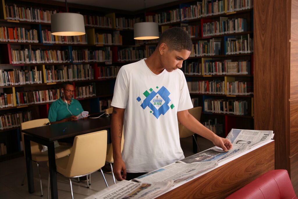 Jovem lendo notícias do jornal diária na Biblioteca Salomão Malina/ Arte: FAP